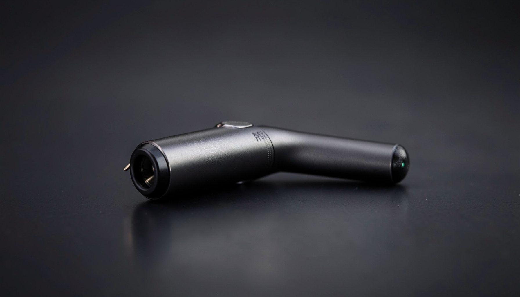 Mid-sized vape pen on a dark gradient surface with subtle reflections in charcoal and gunmetal tones