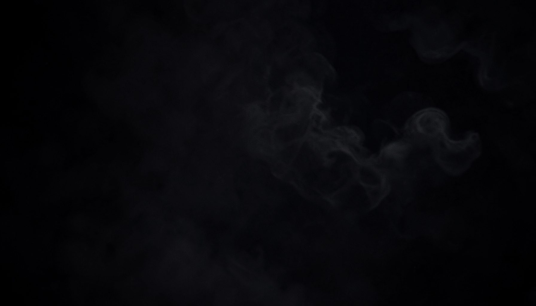 Dark atmospheric backdrop with subtle vapor wisps and deep charcoal tones, conveying a sleek premium lifestyle mood